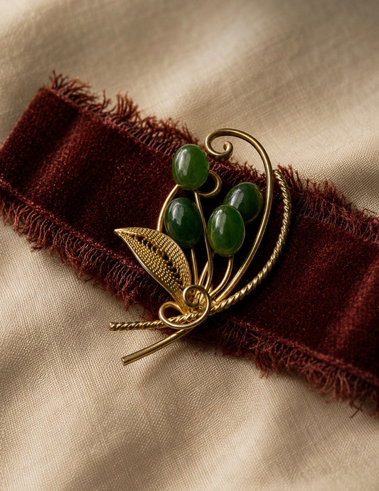 Gold tone filigree brooch with green beads, featuring a leaf and vine design.