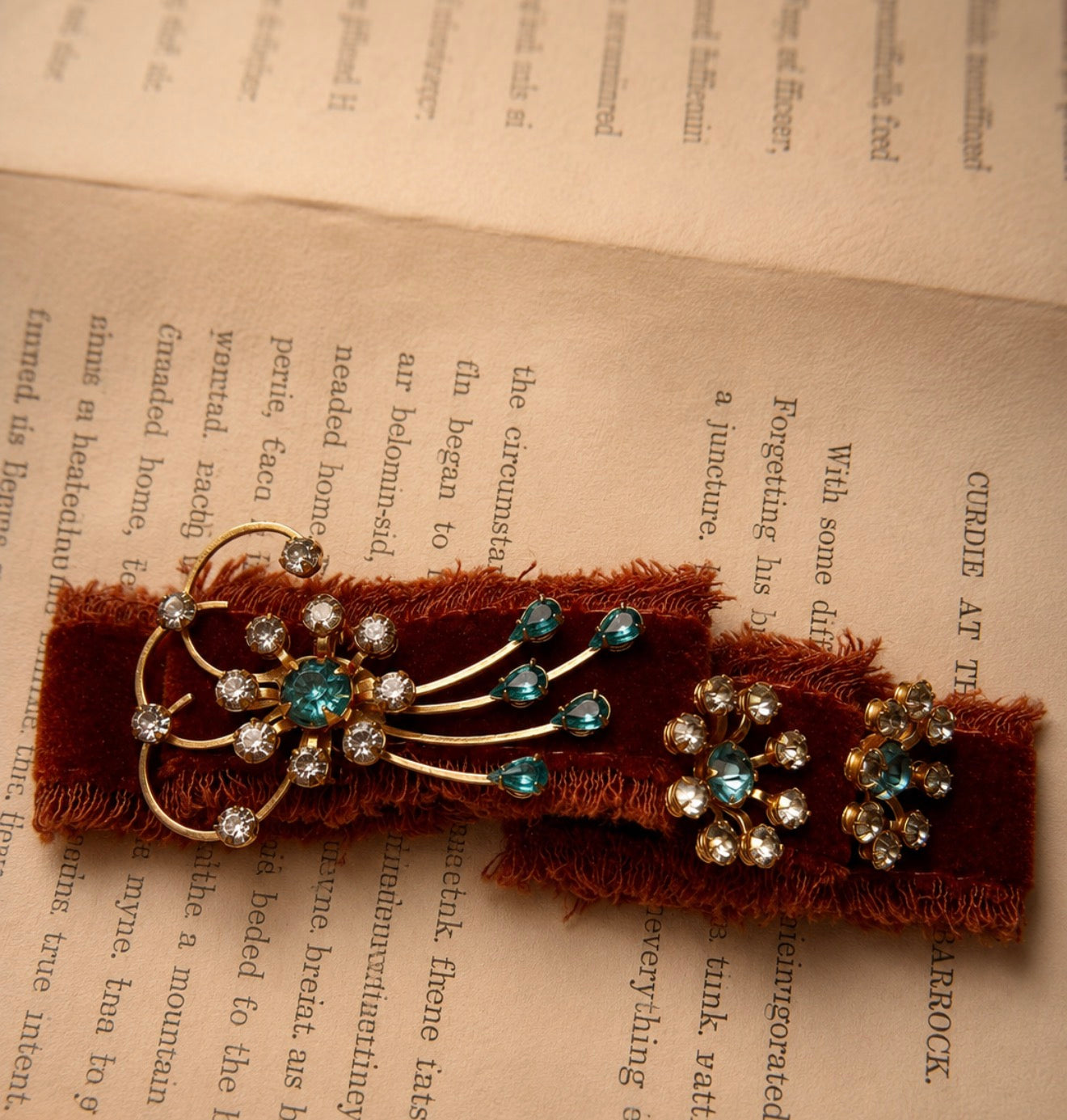 Gold starburst brooch with blue and clear rhinestones on velvet, next to matching screw-back earrings.