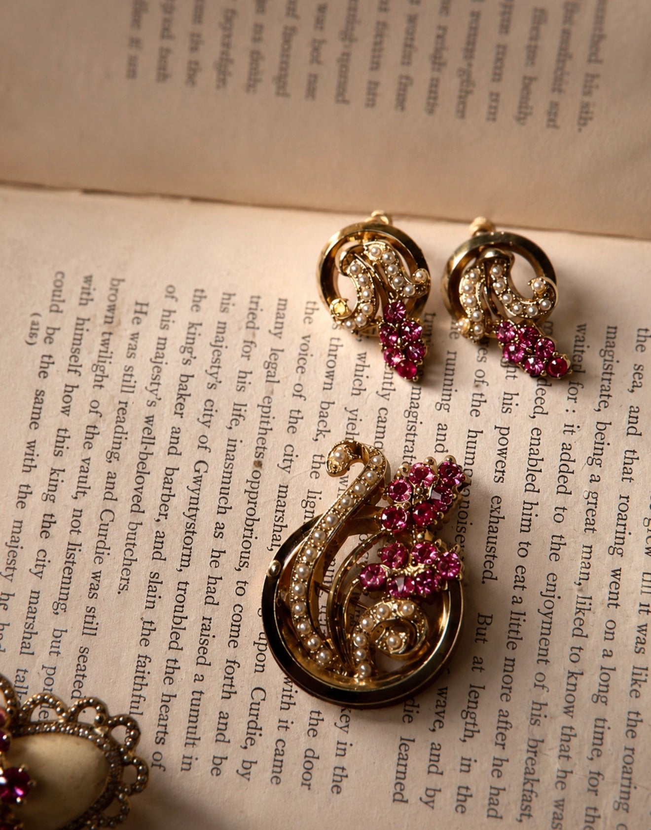 1940s pink rhinestone and faux pearl brooch and earrings set on an open book.